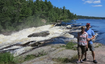 photo of a smiling couple standing in front of rapids